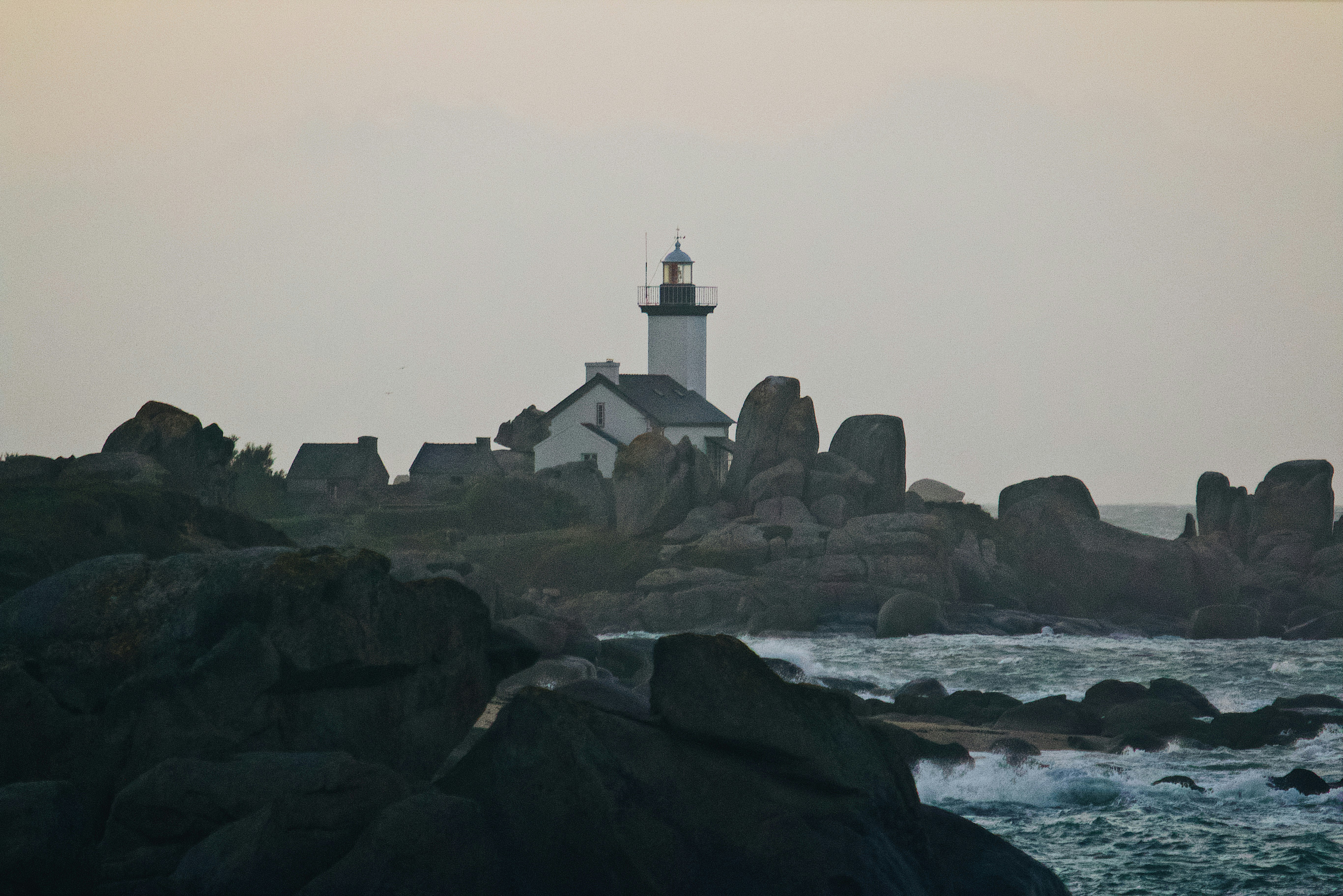 white and black lighthouse on rocky shore during daytime